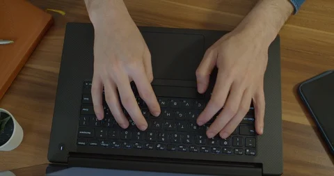 Man hands typing text on laptop keyboard at wooden desk. Man using notebook for Stock Footage 129460563