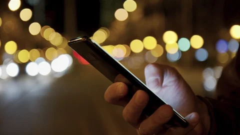 Man hands typing text message smartphone at night city street. Connecting and Stock Footage 128033155
