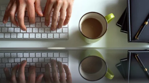 Man hands typing on white keyboard surrounded by notebooks, cup of coffee and Stock-Footage 115054655