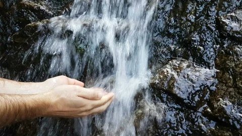 Man hands under the water of a waterfall in the mountains Stock Footage 95697745