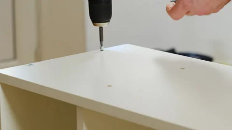 Man hands use electric screwdriver for installing screw into shelf wall Video stock 304397457