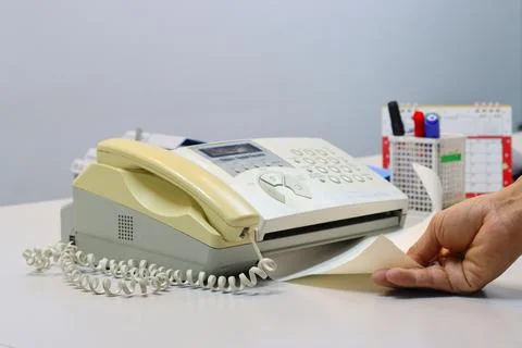 Man hands using a fax machine, putting paper Stock Photos