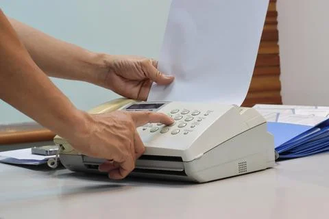 Man hands using a fax machine, putting paper 库存照片