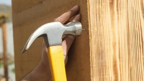 Man hands using hammer to drive nail securing back panel of wooden cabinet made  Stock Footage 332875592