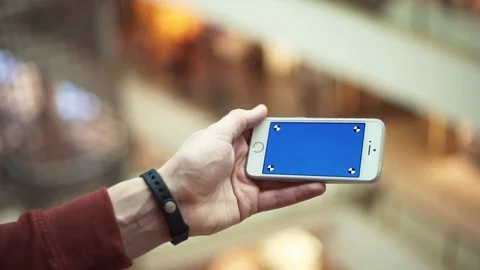 Man hands using smartphone with blue screen in shopping mall Stock Footage 82989643