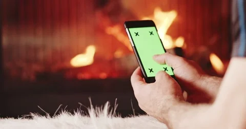 Man Hands Using SmartPhone with Green Screen by Fireplace. 4K SLOW MOTION 스톡 동영상 69260472