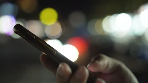 Man hands using smartphone at night on bokeh color light in night city street Video stock 93676999