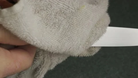 Man Hands Wiping a Razor-Sharp Knife with a Soft Towel a close-up shot lifestyle Stock Footage 232348691