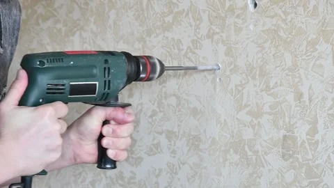 Man hands work with drill tool to make hole in wall. Home improvement. Slow Stock Footage 153932701