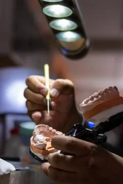 Man hands working in a prosthetic ceramic tooth Stock Photos