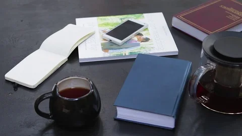 Man hands writing in the notebook. Teapot, cup, notebook and books around. Video stock 76969672