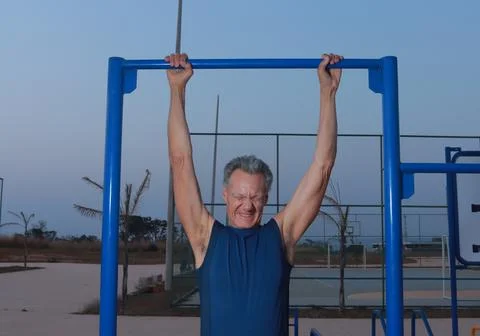 Man Hanging and Stretching from a Pull Bar at an outdoor Fitness Park Foto stock