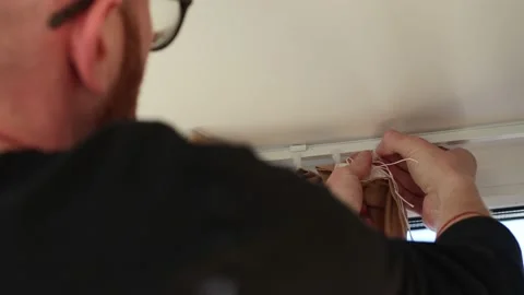 Man hanging curtains on a plastic hooks. 4K. Stock Footage 200107432