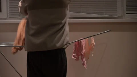 Man hanging laundry on drying rack 動画素材 317050498