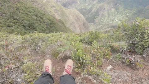 Man hanging out at the edge of a cliff after a long hike Stock Footage 132686388