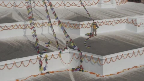 Man hanging prayer flags on Boudha stupa. Stock Footage 241736072