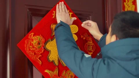 Man Hanging Red Diamond Decoration on Door for Lunar New Year Celebration Stock Footage 336560890