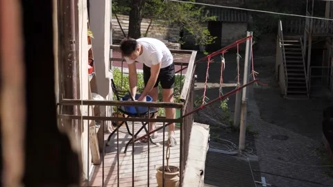 Man hanging things on the balcony Stock Footage 194400461