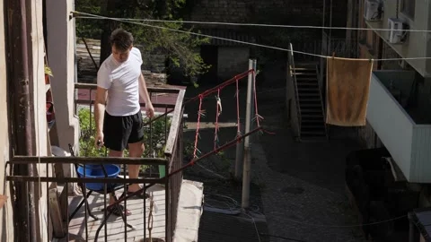 Man hanging things on the balcony Stock Footage 194400599