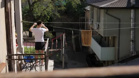 Man hanging things on the balcony Stock Footage 194742838