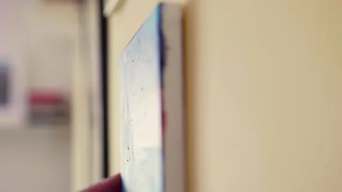 Man hanging a wall art on a wall. Home deorating concept.	 Video stock 306958563