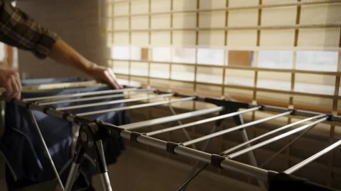 Man hanging wet clothes on drying rack at home.Close-up of a man in a plaid.. Vídeos de archivo 332162387