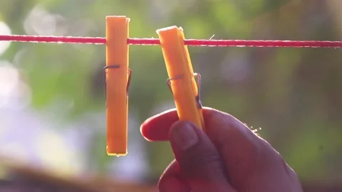 Man hanging yellow-colored drying clips on the rope Stock Footage 162578077