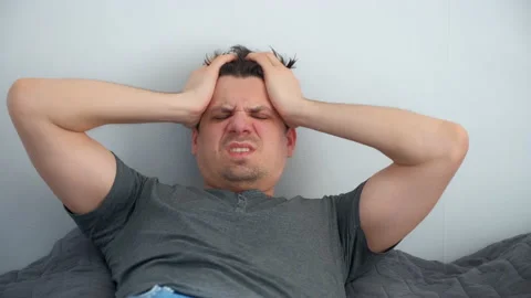 Man with hangover waking up in bed feeling headache looking at camera. Video stock 153367877