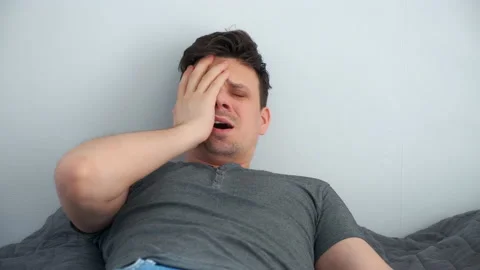 Man with hangover waking up in bed, looking at time on phone and very surprised. Stock Footage 158316658