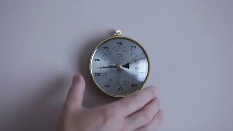 A man hangs a barometer on the wall that... | Stock Video | Pond5