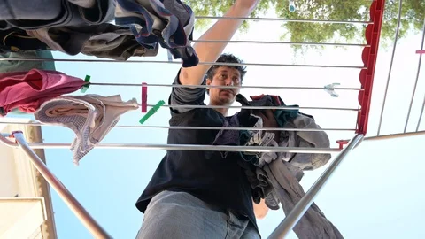 Man hangs clothes to dry on the drying rack outside the house Stock Footage 129981725