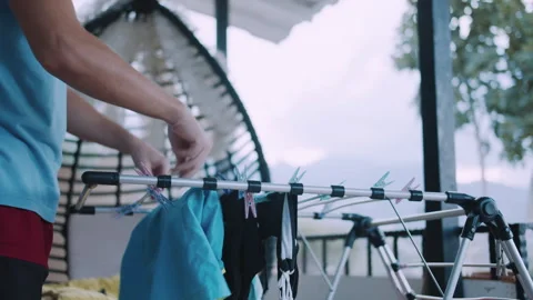 A man hangs dry laundry from a drying rack Stock Footage 329923023
