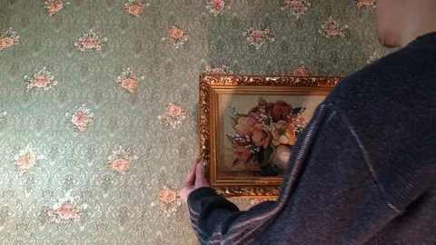 The man hangs a picture on the wall. Stock Footage 105637606