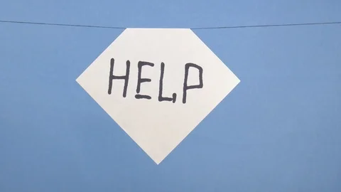 A man hangs a white sheet of paper with a black inscription help on a blue Stock Footage 123786197