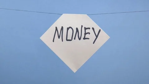 A man hangs a white sheet of paper with a black inscription money on a blue Stock Footage 123786543