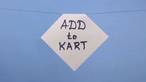 A man hangs a white sheet of paper with a black inscription "add to kart" on a Video stock 123858674