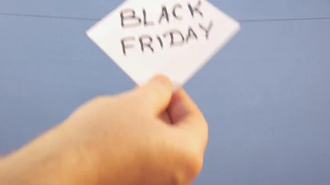 A man hangs a white sheet of paper with a black inscription "black friday" on a Stock Footage 123858906