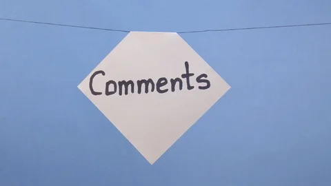 A man hangs a white sheet of paper with a black inscription "comments" on a blue Stock Footage 124019409