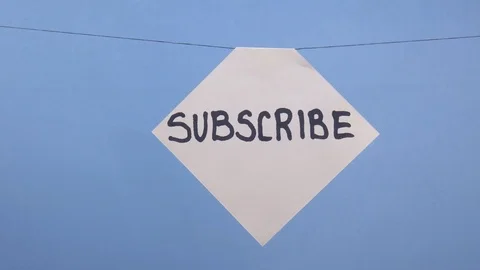 A man hangs a white sheet of paper with a black inscription "subscribe" on a Stock Footage 124175504