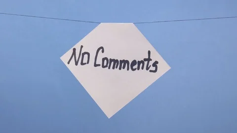 A man hangs a white sheet of paper with a black inscription "no comments" on a Stock Footage 124203372