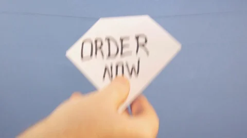 A man hangs a white sheet of paper with a black inscription "order now" on a Video stock 124203567
