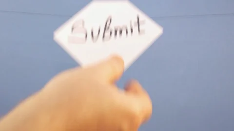 A man hangs a white sheet of paper with a black inscription "submit" on a blue Stock Footage 124266388