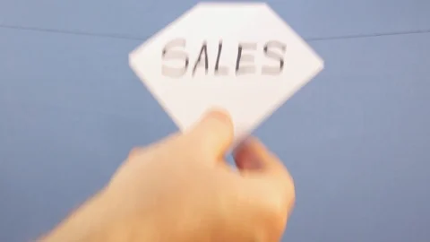 A man hangs a white sheet of paper with a black inscription "sales" on a blue Stock Footage 124370647