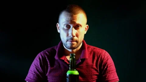 Man happily drinks beer from a bottle on a dark green background Stock-Footage 134951722