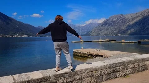 A man happily walking along the seaside promenade with a scenic view Stock Footage 237998902