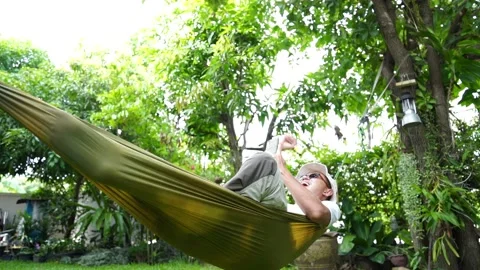  man happy happiest lying on his phone on a hammock in the garden Video stock 172084953
