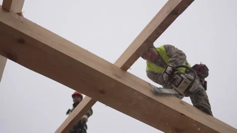 Man in hard hat actively uses chainsaw to cut wooden beam Vídeo Stock 311106154
