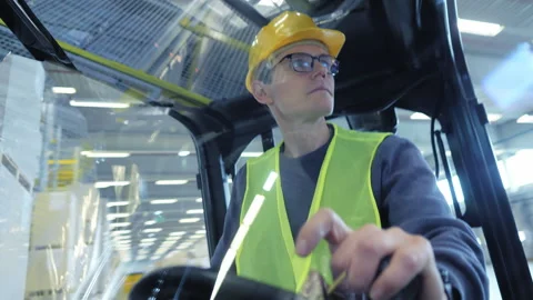 Man in hard hat and safety vest operating forklift in warehouse. 库存影片 307998061