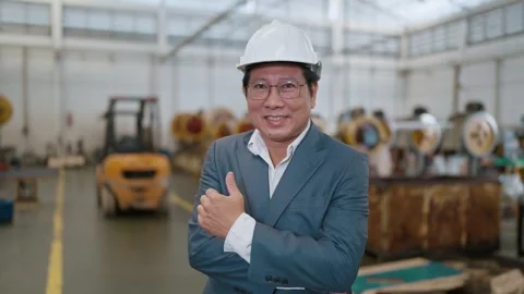 Man in hard hat smiles confidently in industrial setting Stock Footage 338066338