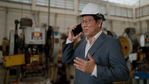 Man in hard hat speaks on phone within factory Stock Footage 338066344